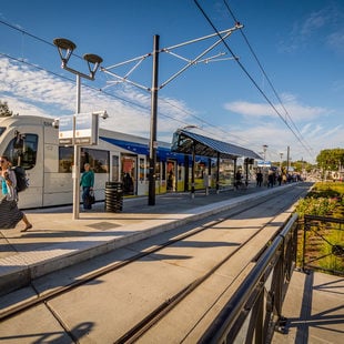 portrait of a MAX light rail train with a few people walking on the train platform