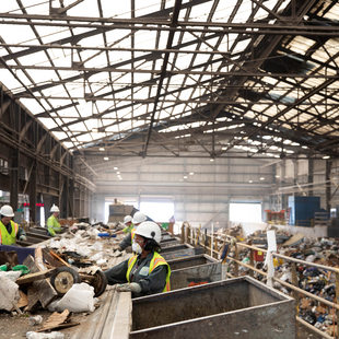 workers near a conveyor belt sort recyclable material from garbage