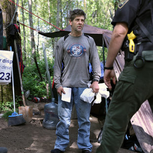 A man holding white Metro trash bags talks with outreach workers.