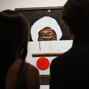 Two people look at a portrait of an African American man