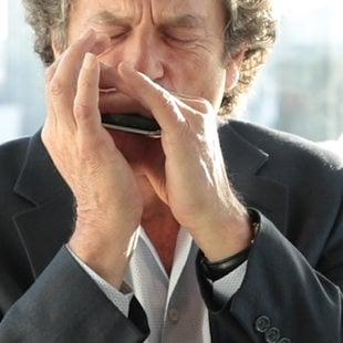 A man riffing on a harmonica