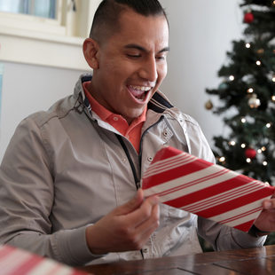 A man reacts with excitement to a festively wrapped holiday present