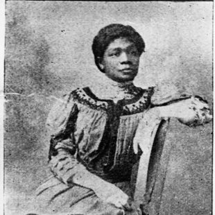 A sophisticated, lovely black woman wearing an embroidered dress and white gloves  poses for a black-and-white photograph
