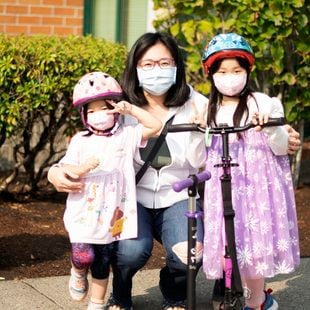 Mother and two children pose wearing masks and helmets