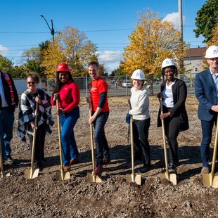 Seven people with golden shovels breaking ground 