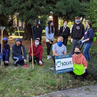 An image of volunteers with garden tools standing behind a SOLVE sign