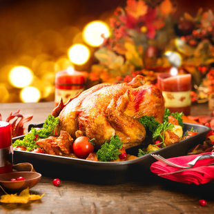 Image of a holiday dinner table featuring a roasted turkey and candles