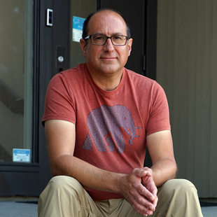 Man with red shirt and khakis sitting on steps