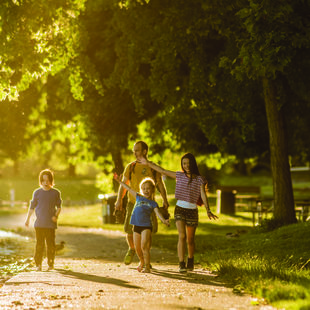A family of four, including two young kids, walk along a tree-lined path at Blue Lake Regional Park.