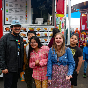 A group of youth pose for a photo in front of a food cart at The Yard at Montavilla food cart pod