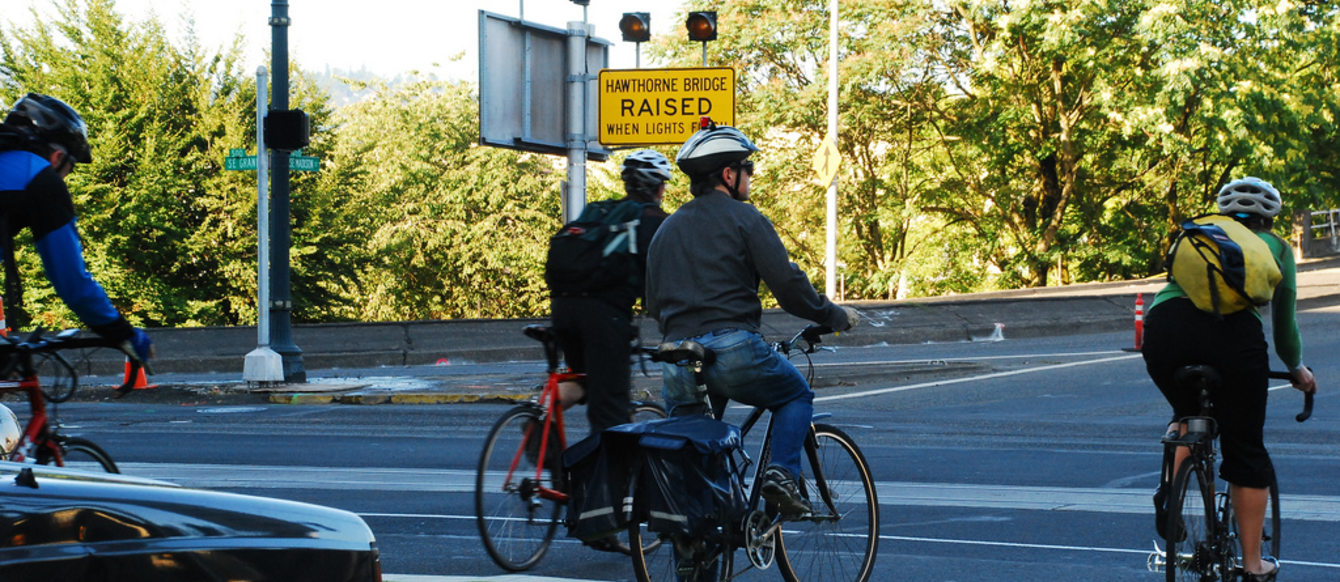 a photo of a group of cyclists riding their bicycles beside cars