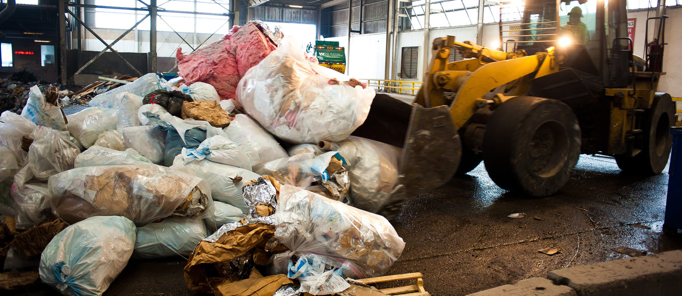 photo of a backhoe moving garbage at a transfer station