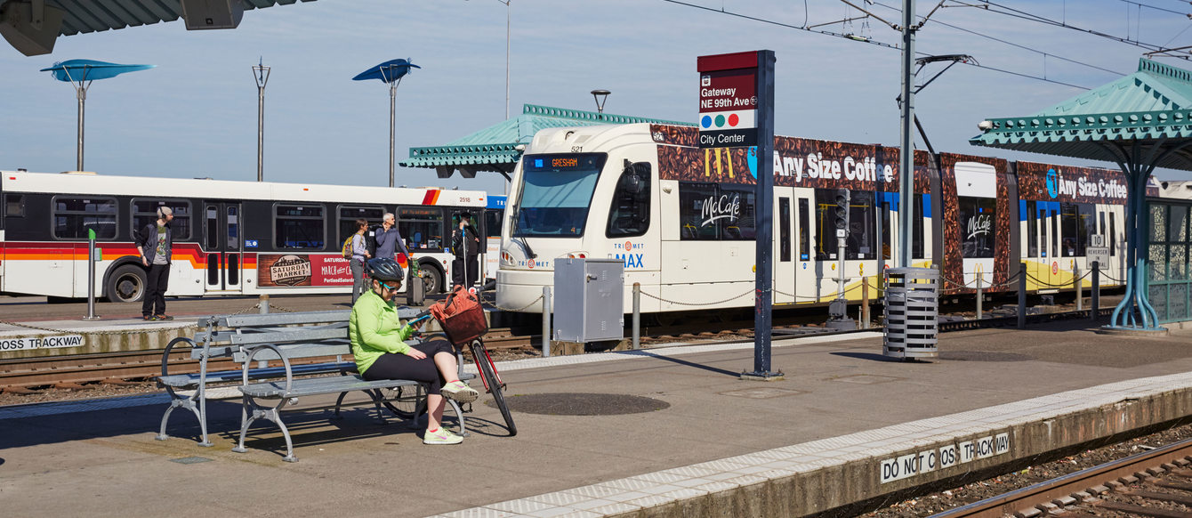 The Gateway MAX station with people waiting for light rail and boarding a bus.