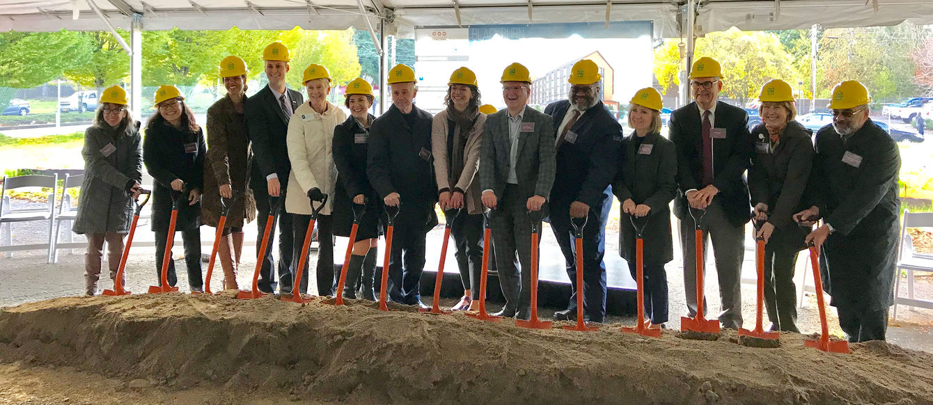 Elected officials pose for a portrait with shovels and hard hats during a groundbreaking ceremony.