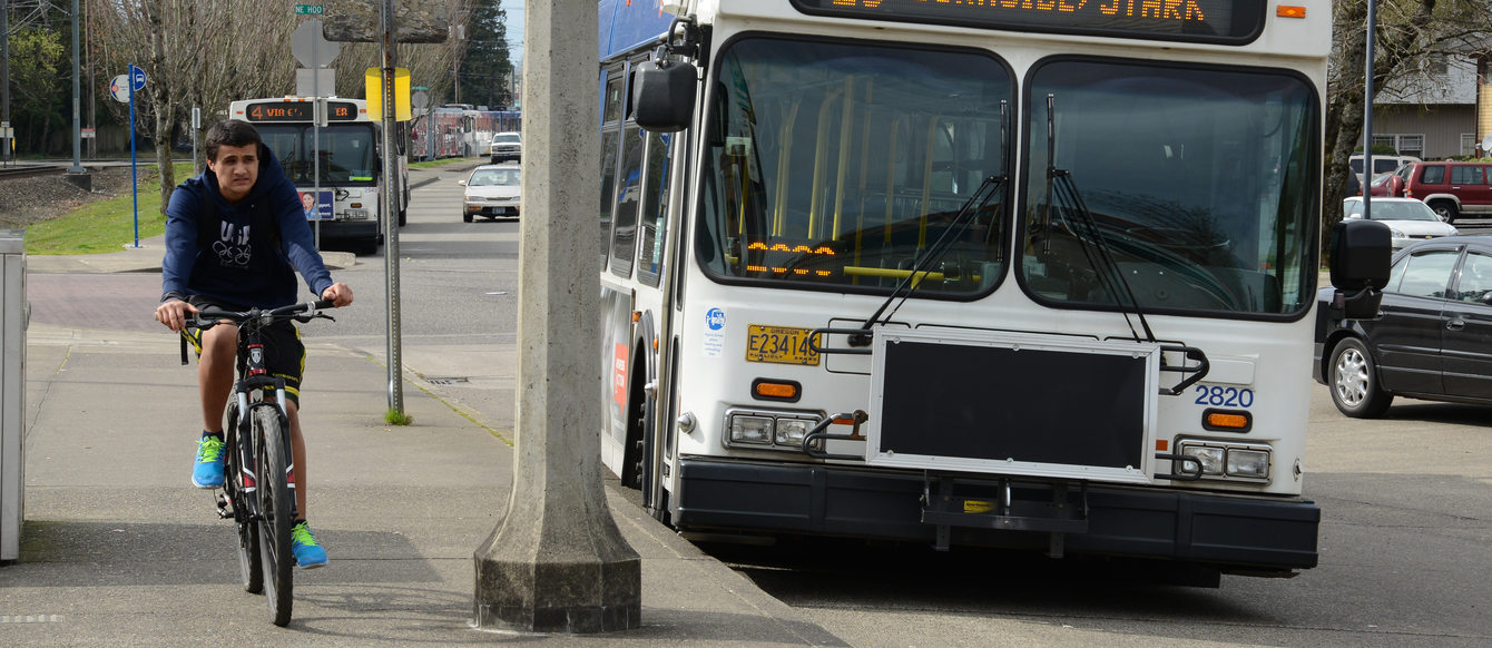 A bicyclist rides alongside a TriMet bus.