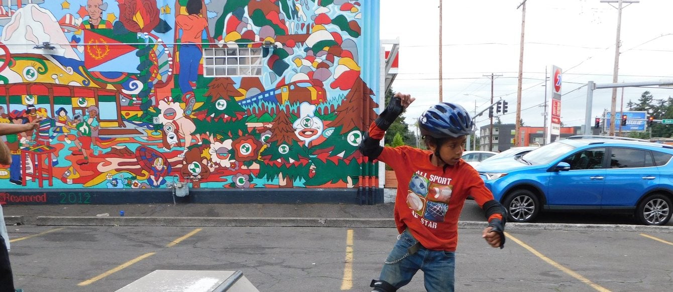 a little boy on a skateboard with a mural as a backdrop