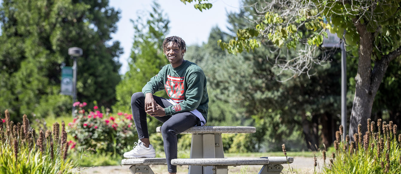 A young man sits on a picnic table, posing for a portrait.