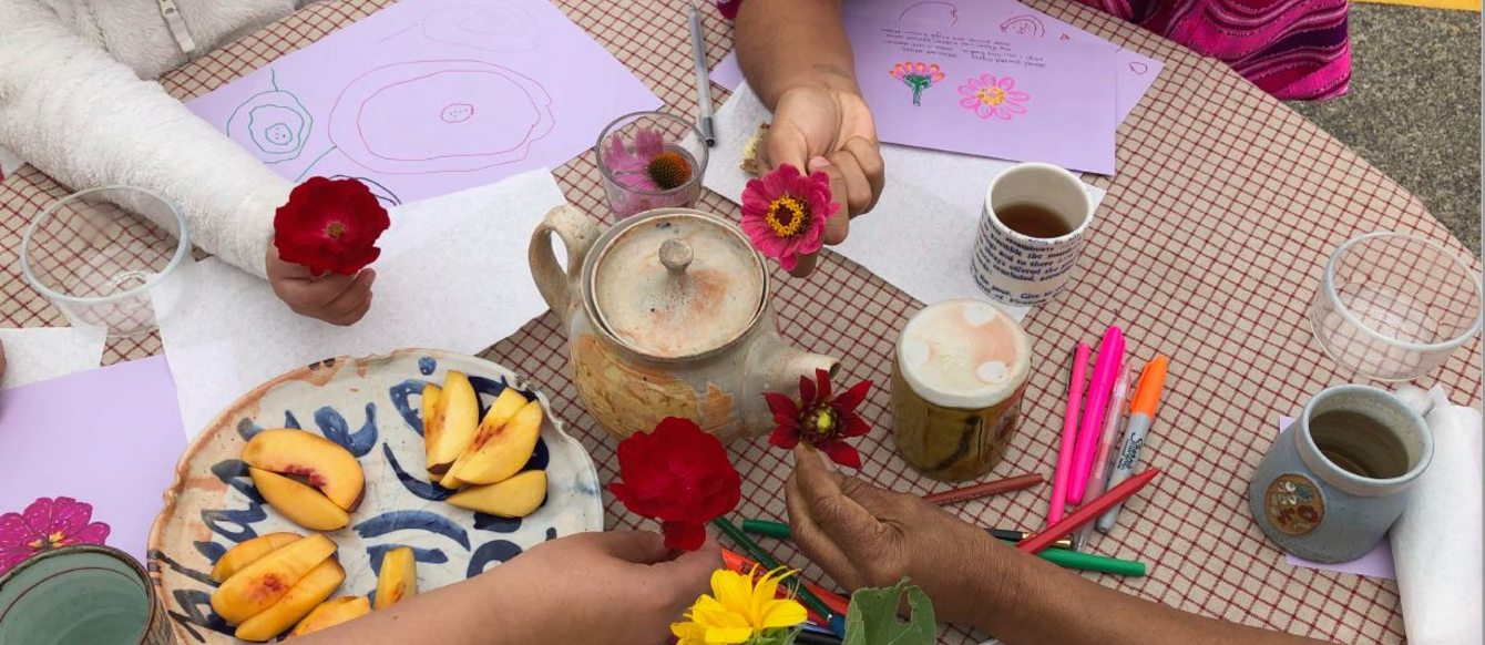 Four people sit around a crafting table holding flowers