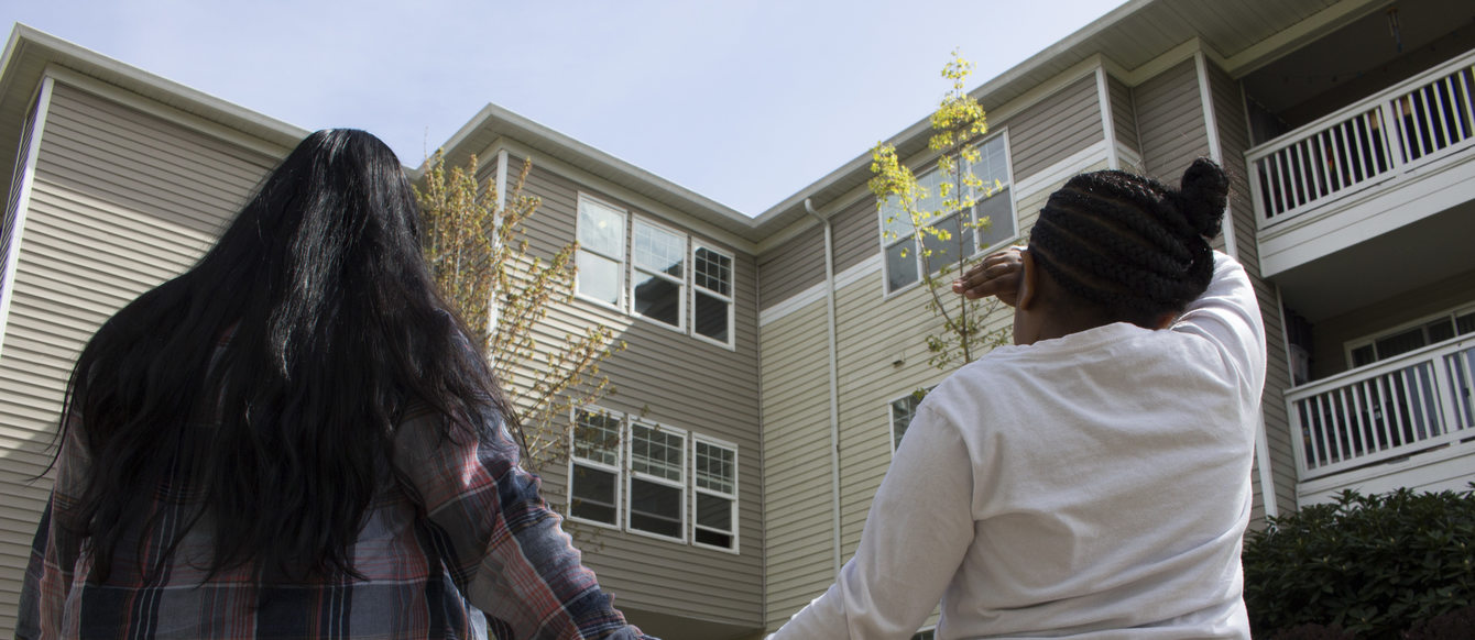 woman and daughter holding hands and looking at an apartment building