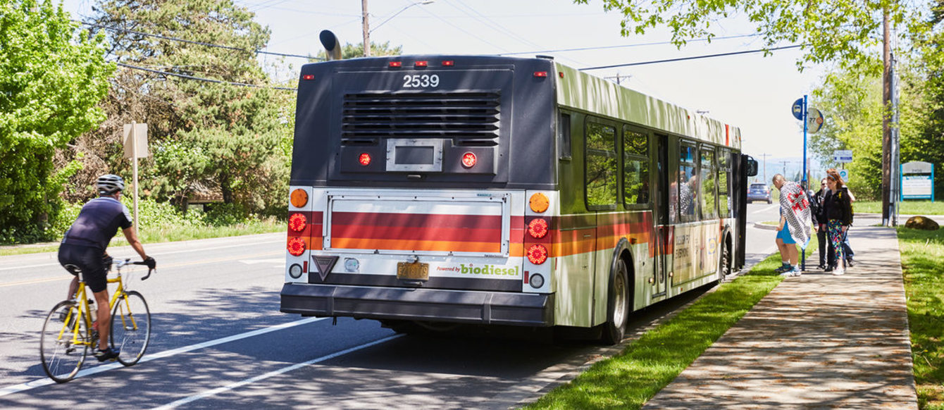 Bus stops for riders and cyclists ride by