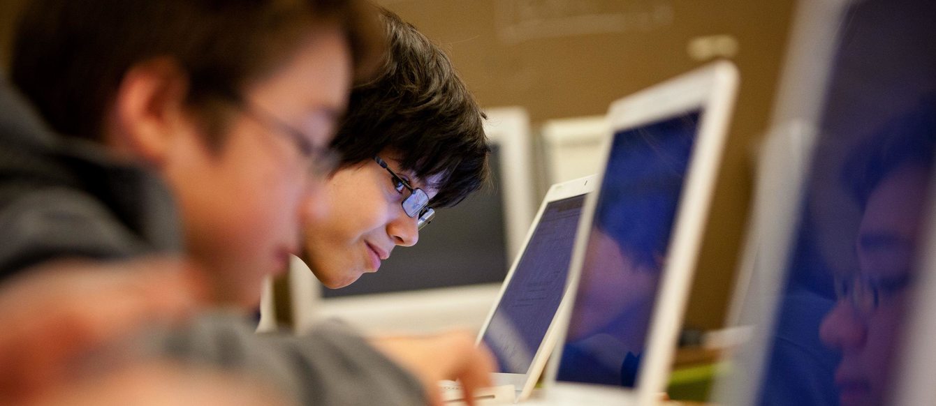 kids typing on laptops while sitting next to each other in a school computer lab