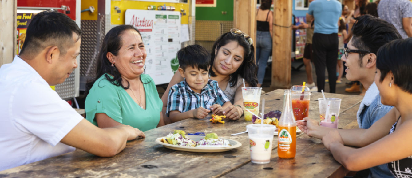 Family eats at a table in front of food trucks