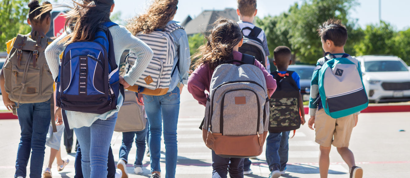 Group of student walking away from the camera as they cross a street