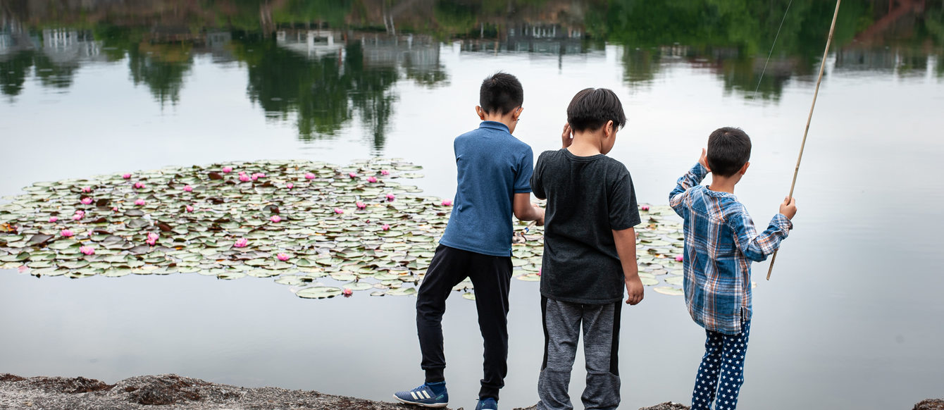 Three kids fishing from the shoreline at Blue Lake Park