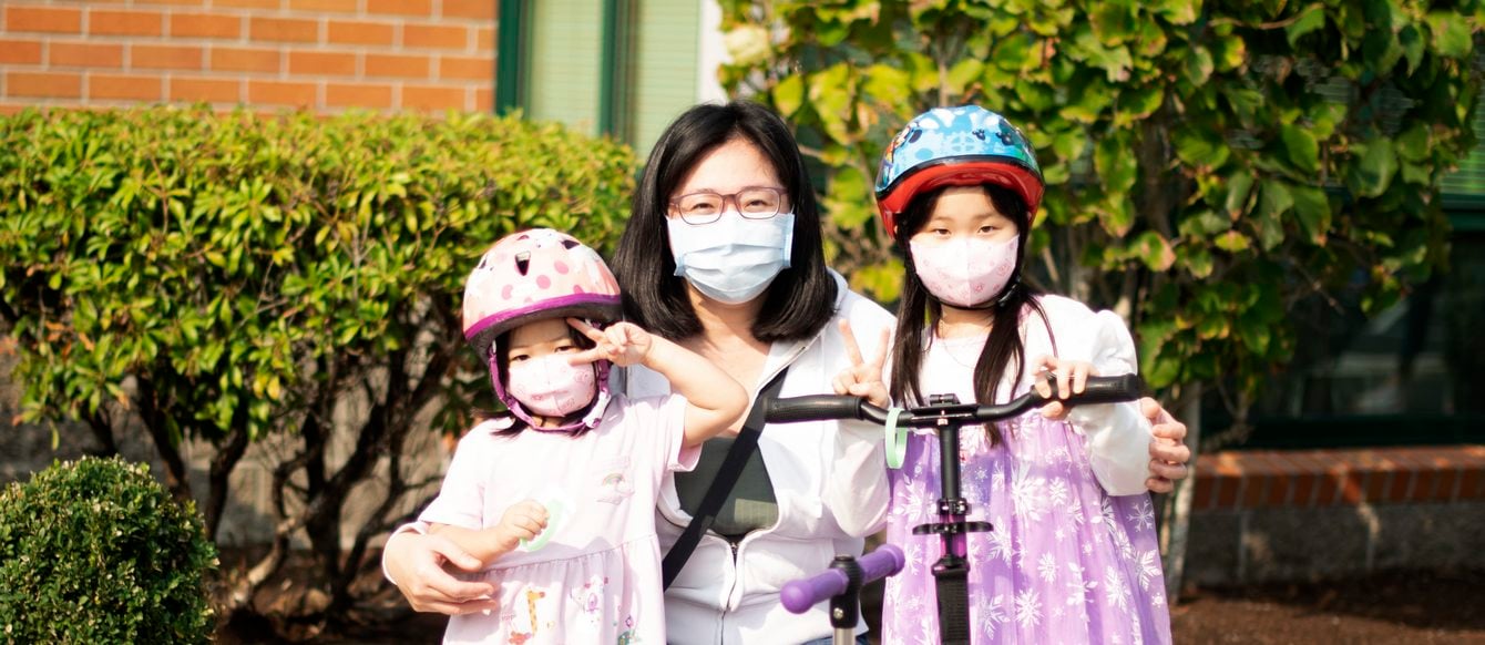 Mother and two children pose wearing masks and helmets