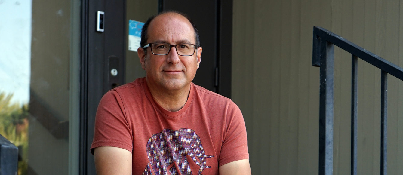 Man with red shirt and khakis sitting on steps