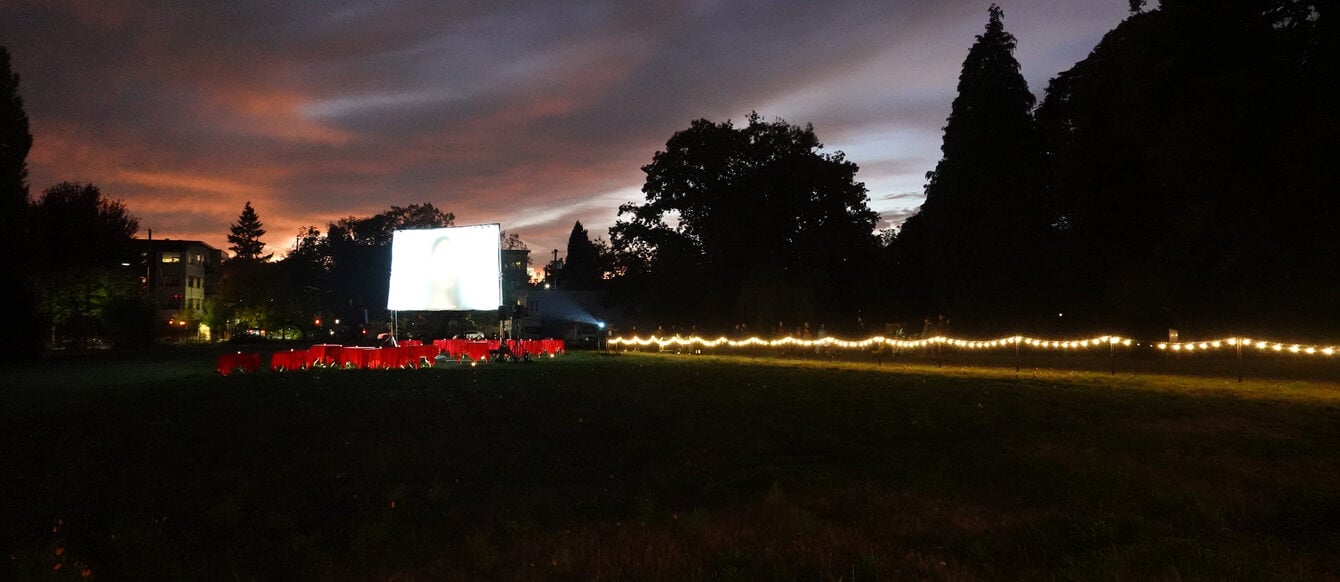 A wide view of Block 14 with the Serenading the Departed projection screen, tables and audience in the background.