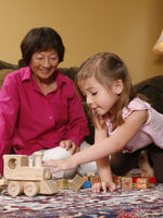 photo of a grandmother and child playing with a wooden train