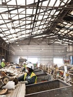workers near a conveyor belt sort recyclable material from garbage