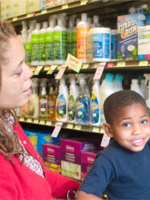 A woman and child are in the cleaning aisle in a grocery store looking at less toxic cleaners