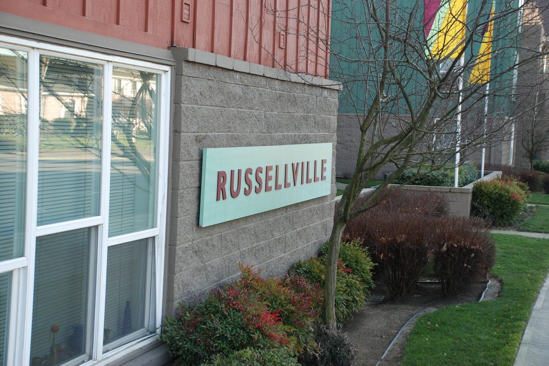 a sign on the brick exterior of a building that says Russelville Commons