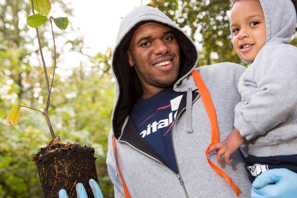 father holding his son and a sapling tree to be planted