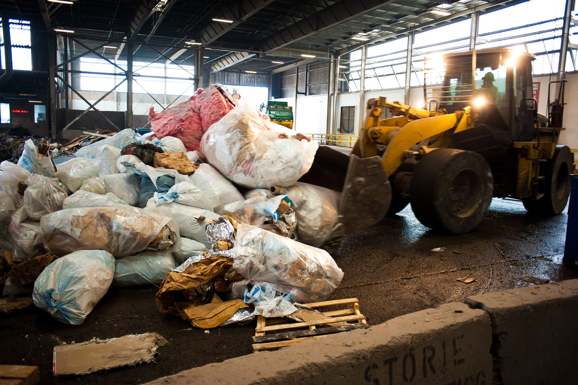 photo of a backhoe moving garbage at a transfer station