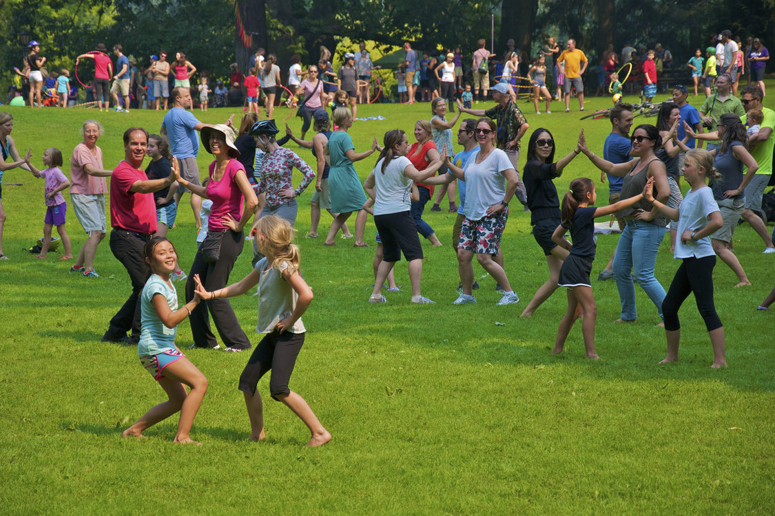 photo of men, women and children dancing in grassy area at Sunday Parkways