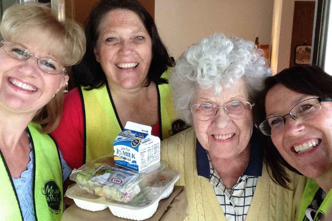 food recipient poses with volunteers