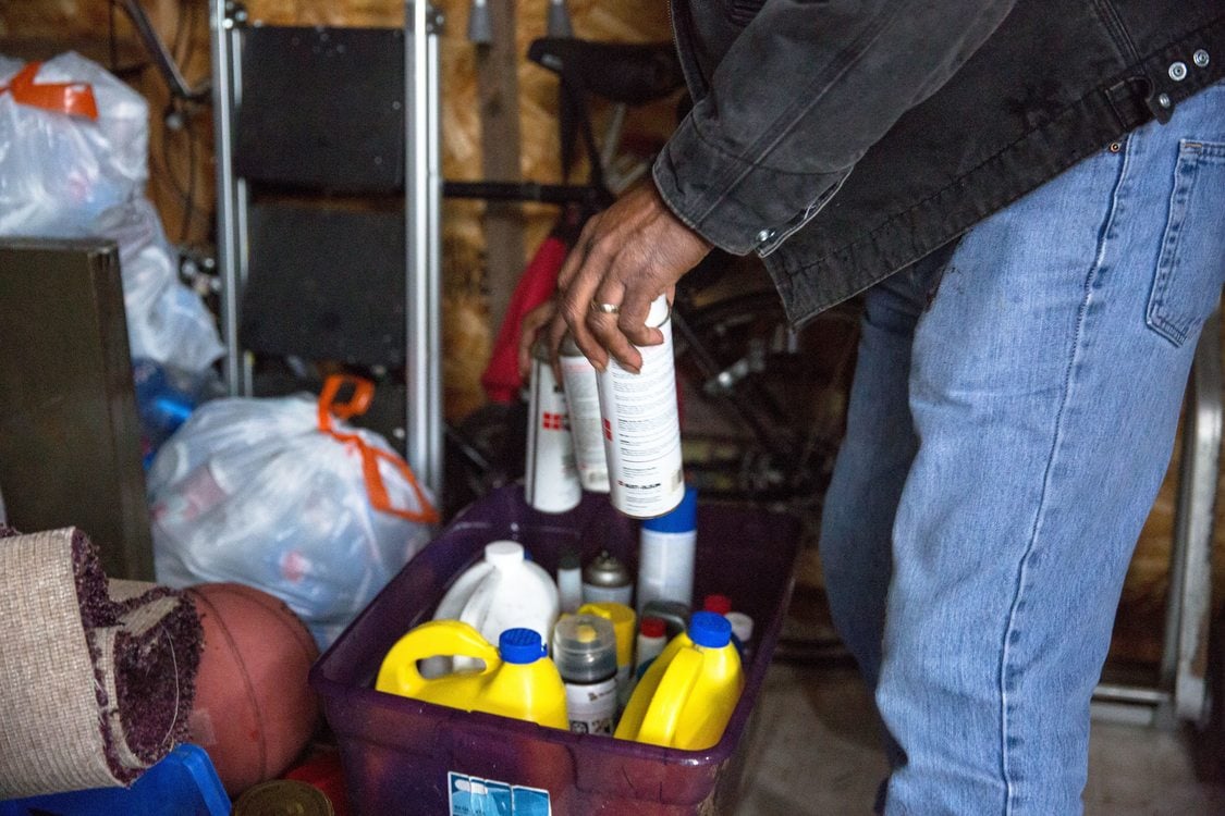 aerosol cans being placed in a recycling bin inside a garage