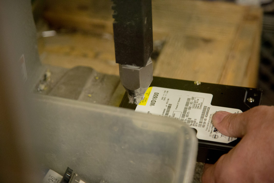 a computer hard drive being rendered inaccessible by punching a hole through it with a specialized tool