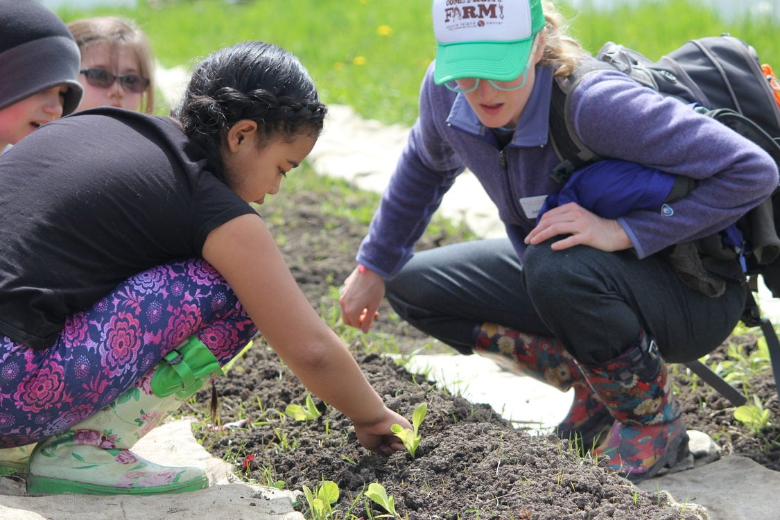 children and an instructor tend to seedlings in a garden at Sauvie Island Center