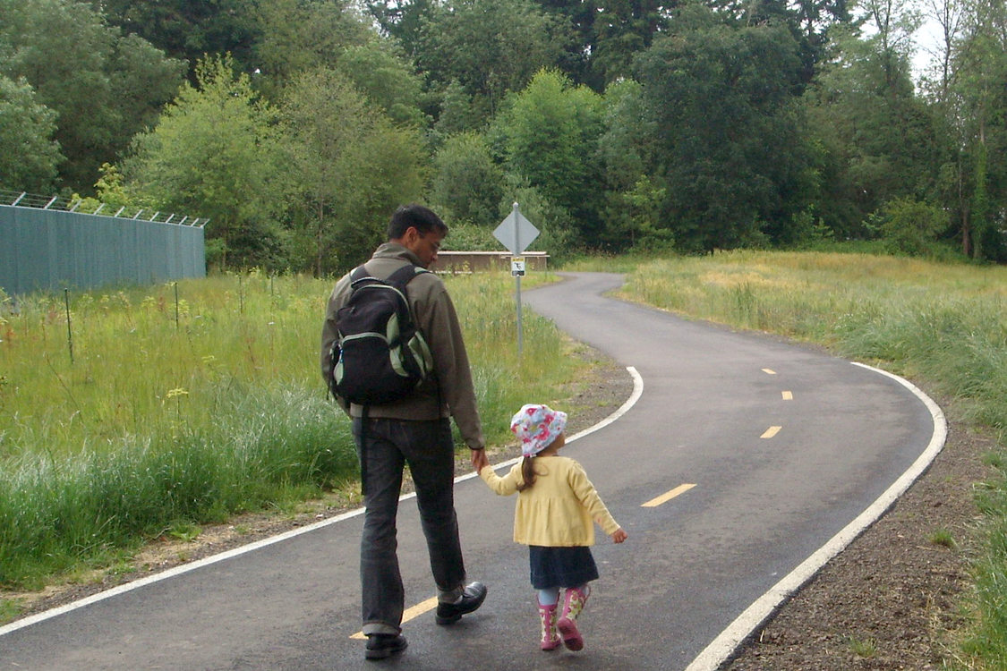 father and young daughter walk together on Fanno Creek Trail