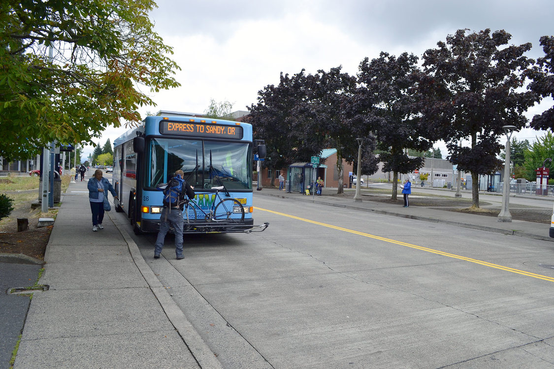 man loading bike onto a Sandy Area Metro bus; woman about to board bus