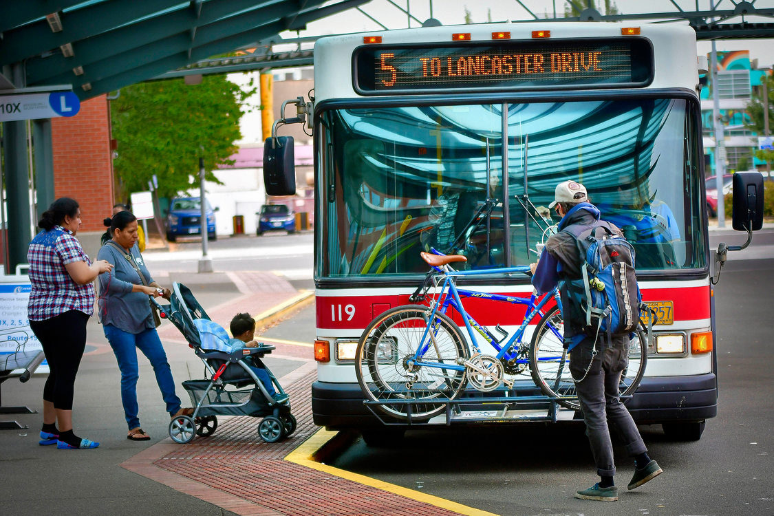 A family boards a Cherriots bus; and a man loads a bike onto the bus' bike rack