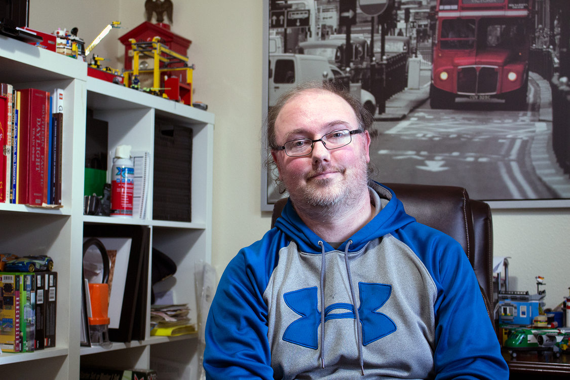 A portrait of Erik  Halstead sitting at his desk in his home office. 