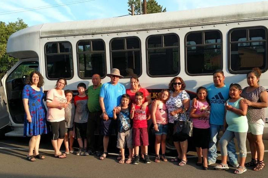 A group of people stand in front of a bus that has been converted to mobile art studio