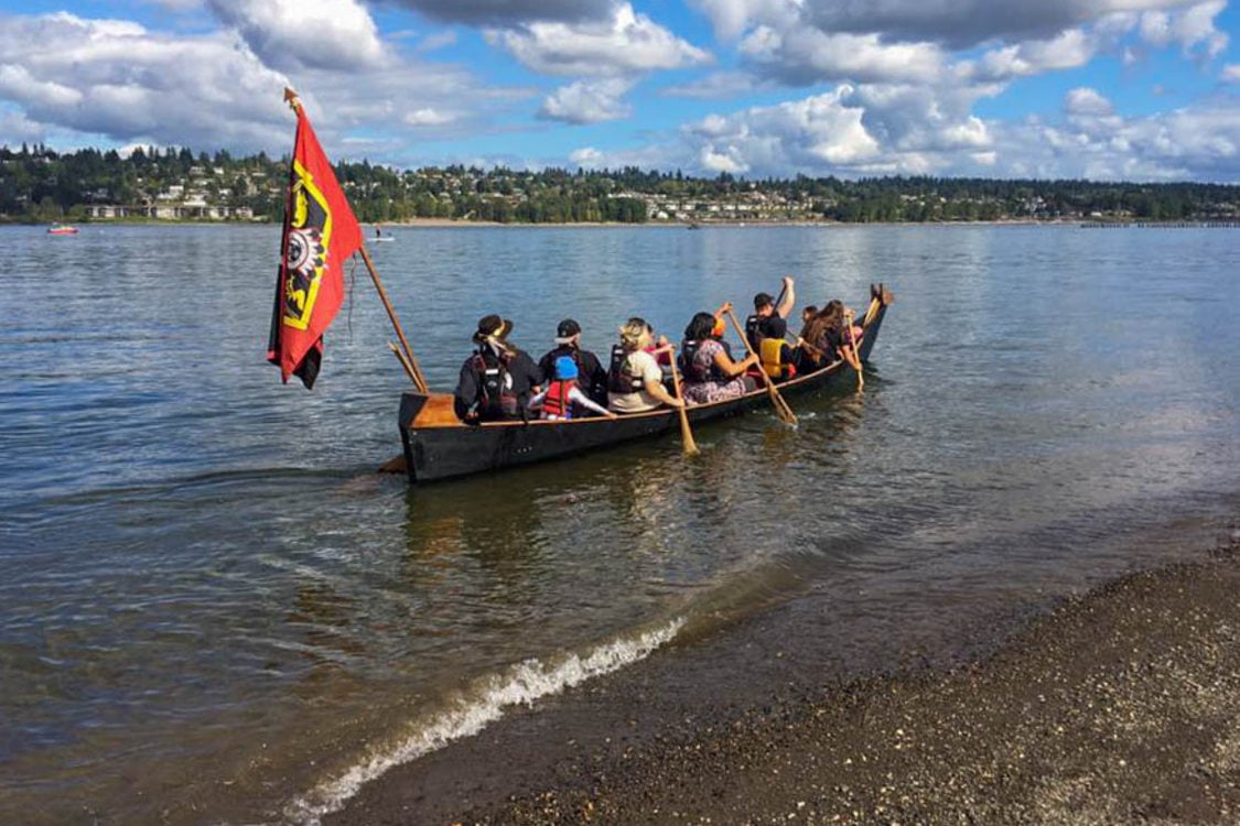 The Portland All Nations Canoe Family launches a canoe on a river