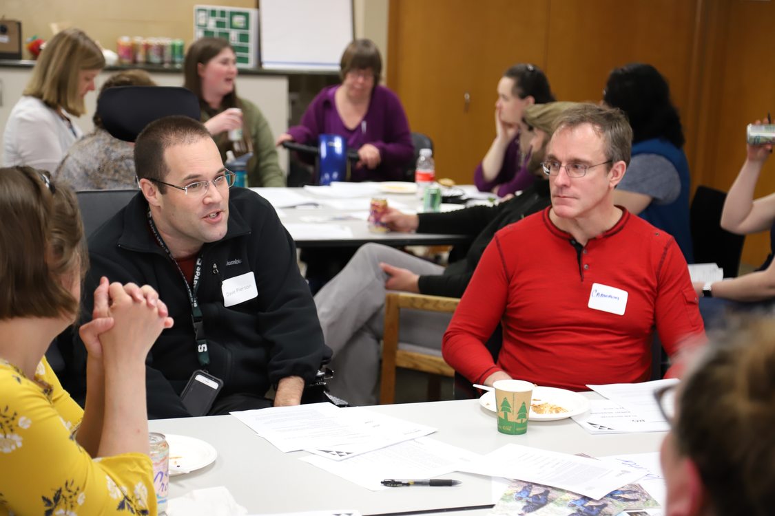 Two people sit at a group discussion table