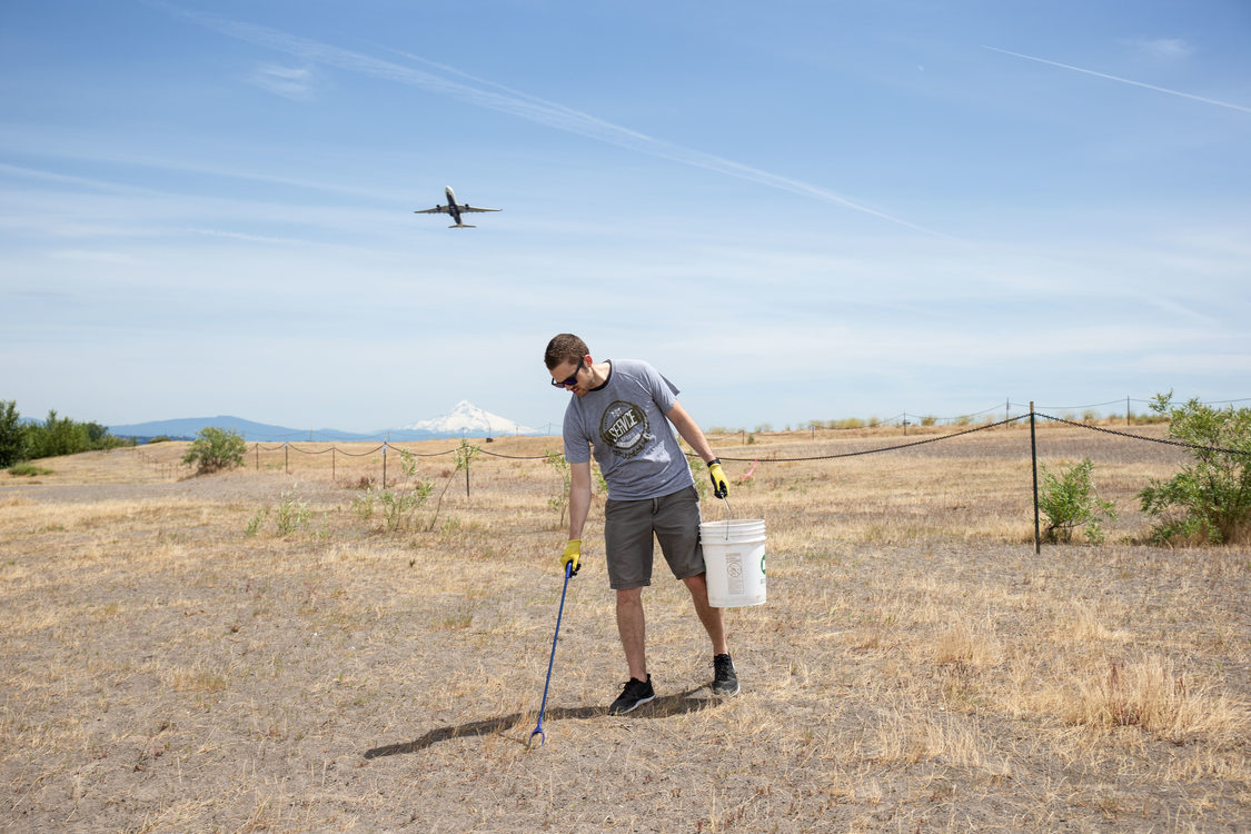 Volunteer uses grabber to pick up trash on Broughton Beach